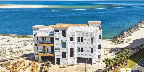 Image 3: Waterfront multi-story structure under construction featuring multiple balconies, direct beach access, and an adjacent parking area