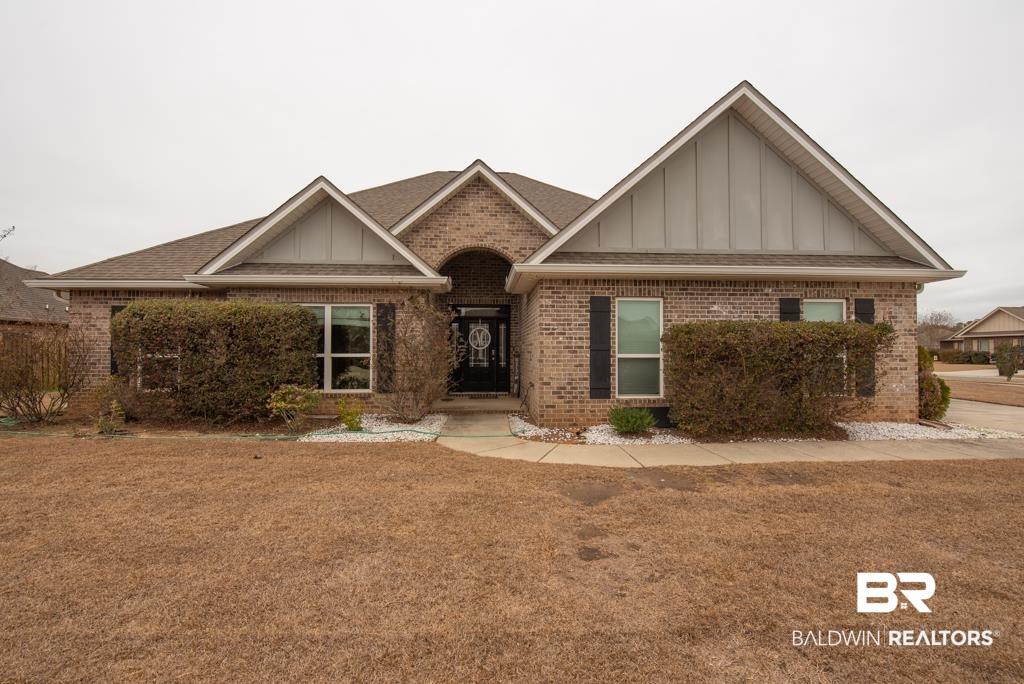Image 2: View of front of property with board and batten siding, brick siding, and a front lawn