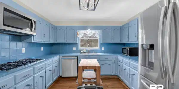 Image 3: Kitchen featuring stainless steel appliances, light countertops, light wood finished floors, and decorative backsplash
