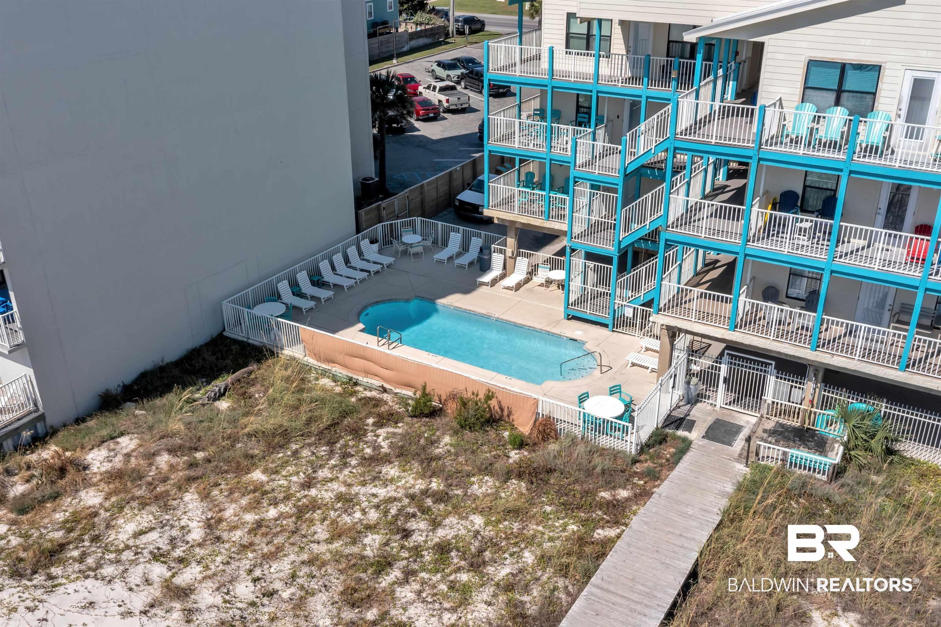 Image 4: Outdoor swimming pool with surrounding patio space, white fencing, and an adjacent boardwalk