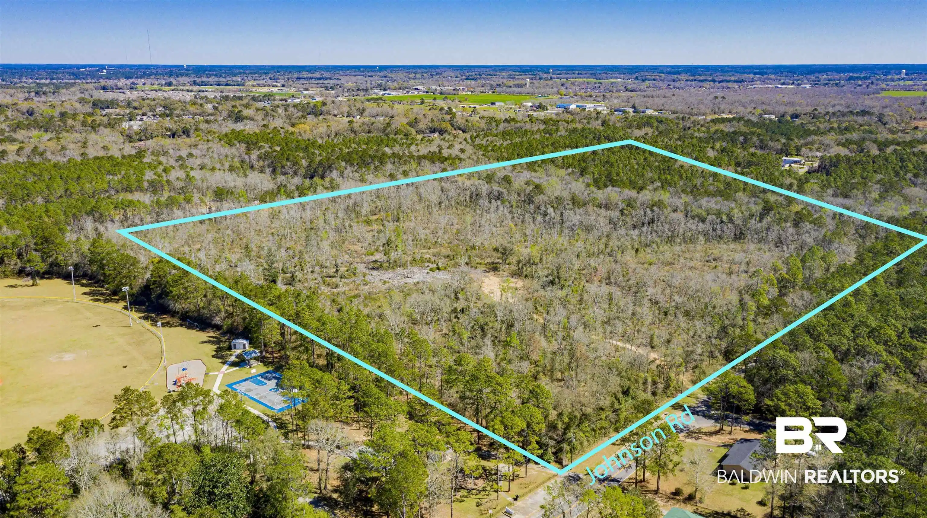 Image 1: Aerial view of property's location with a heavily wooded area and property parcel outlined