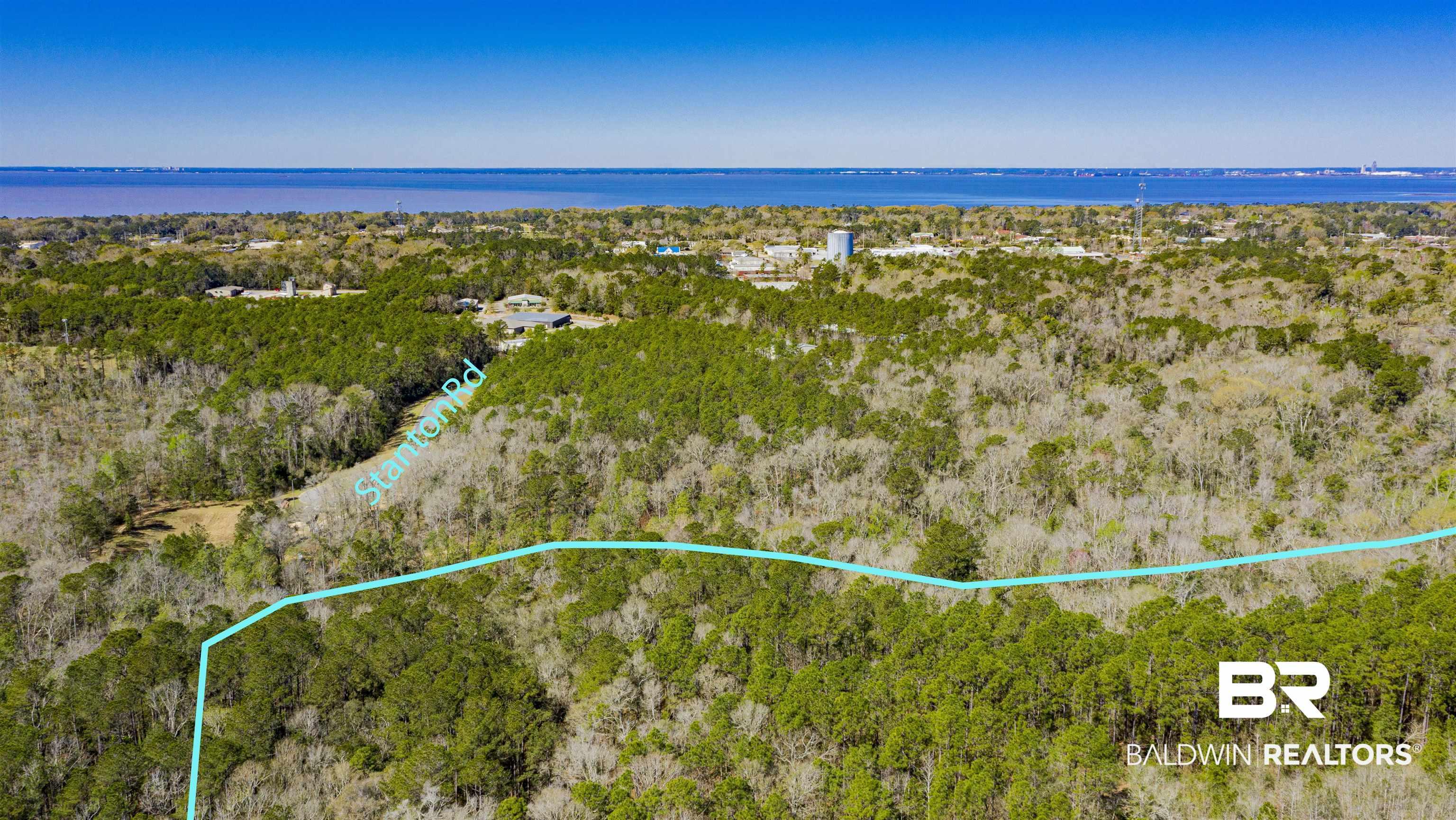 Image 4: Aerial view of property and surrounding area with property parcel outlined and a nearby body of water
