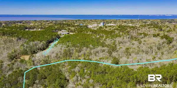 Image 4: Aerial view of property and surrounding area with property parcel outlined and a nearby body of water