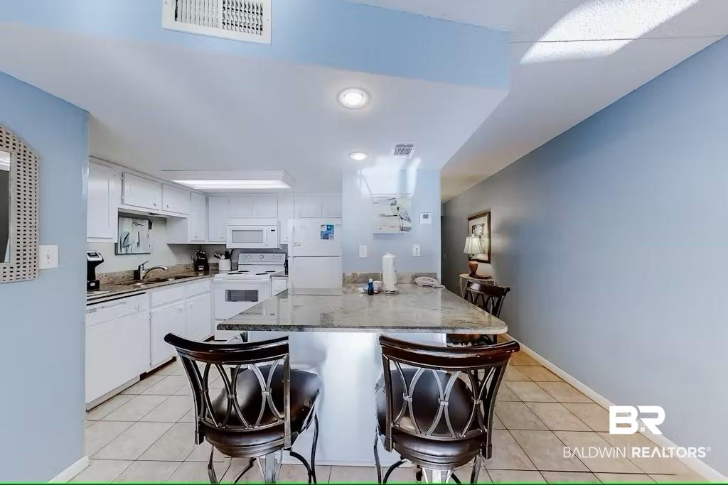 Image 3: Kitchen featuring white cabinetry, white appliances, a center island, and sink