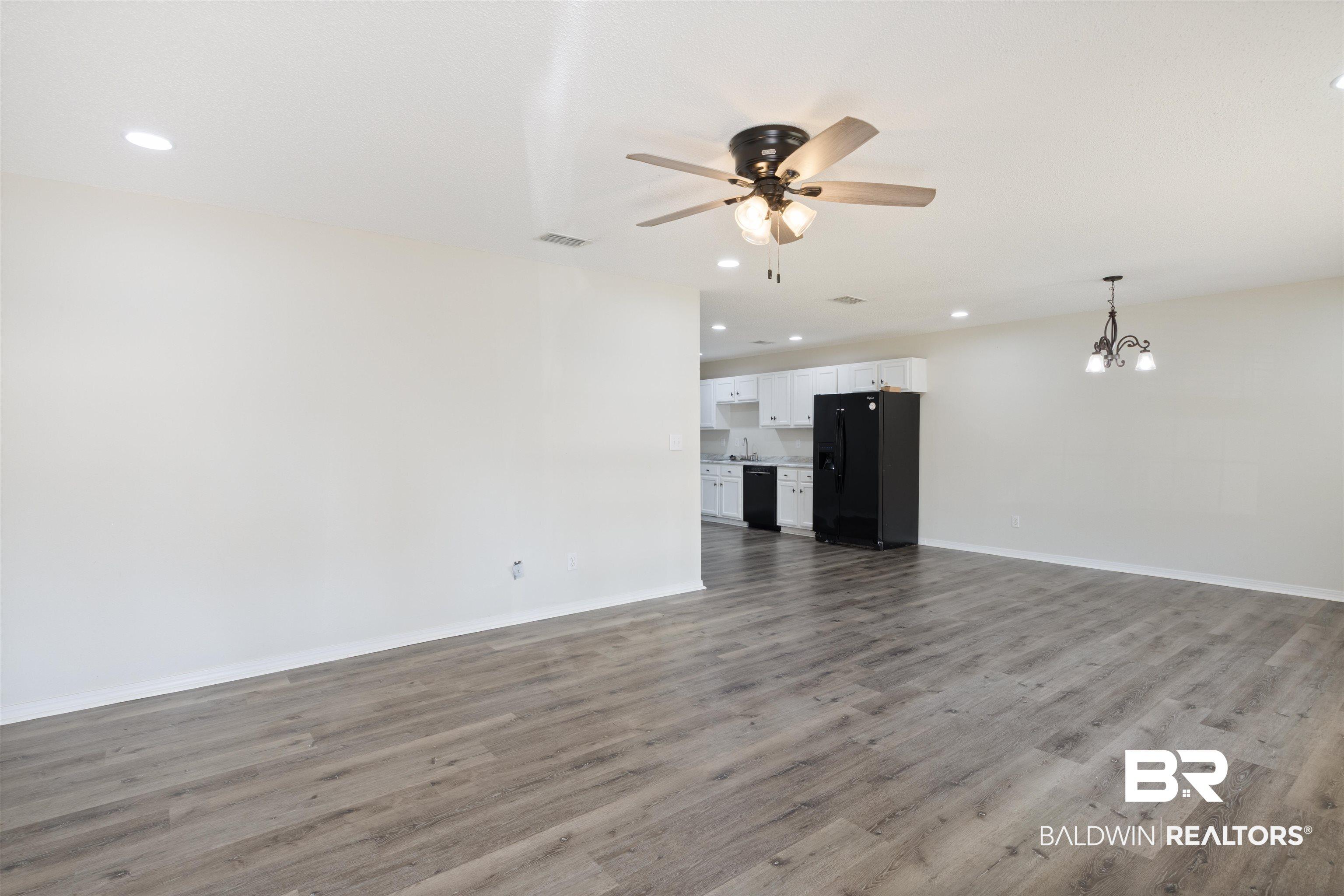 Image 4: Unfurnished living room featuring recessed lighting, a ceiling fan, dark wood-style flooring, and a chandelier