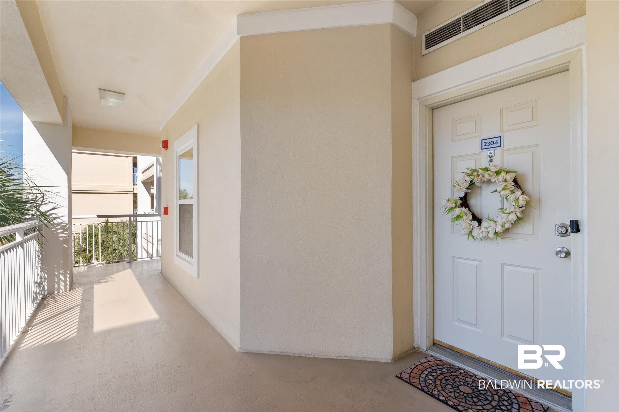 Image 4: View of exterior entry featuring a balcony, visible vents, and stucco siding