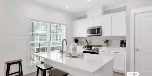 Image 3: Kitchen with stainless steel appliances, white cabinetry, a kitchen bar, an island with sink, and light wood-type flooring