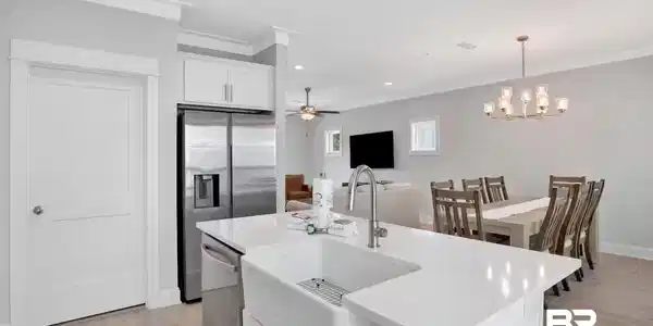 Image 4: Kitchen featuring white cabinets, light wood-style flooring, stainless steel appliances, a kitchen island with sink, and ceiling fan