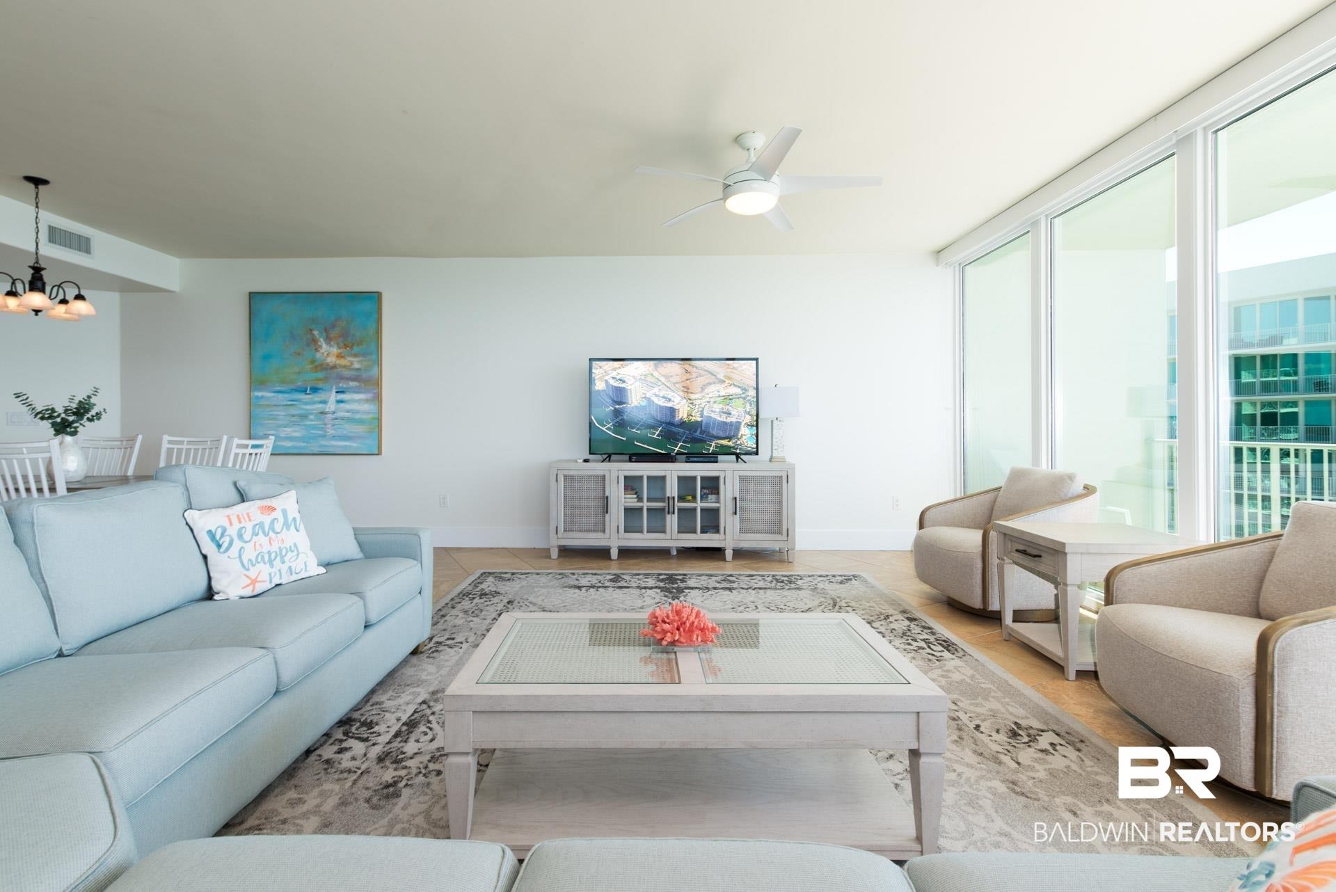 Image 4: Living area featuring a chandelier, floor to ceiling windows, and ceiling fan