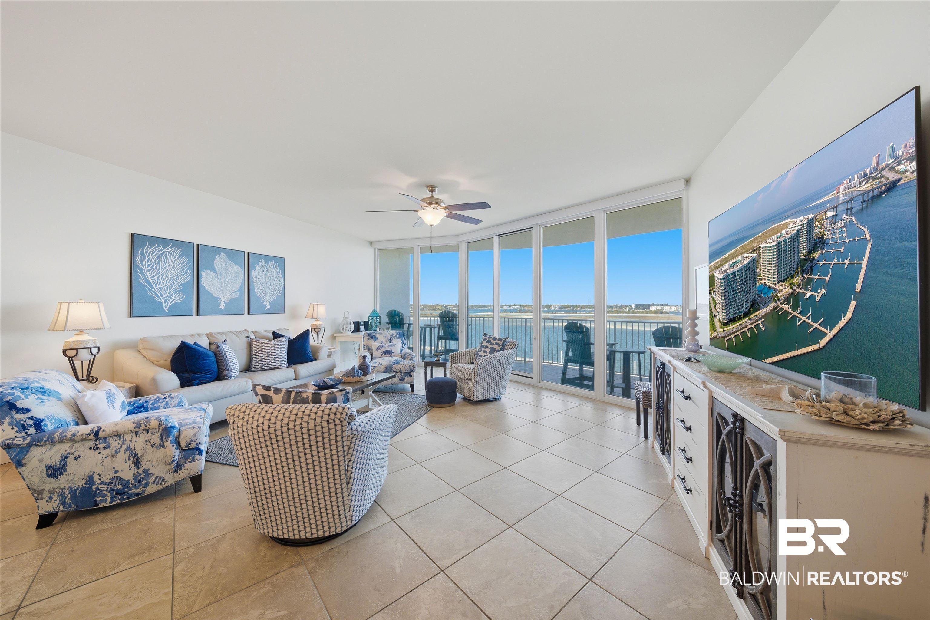 Image 2: Living room with ceiling fan, floor to ceiling windows, and light tile patterned floors