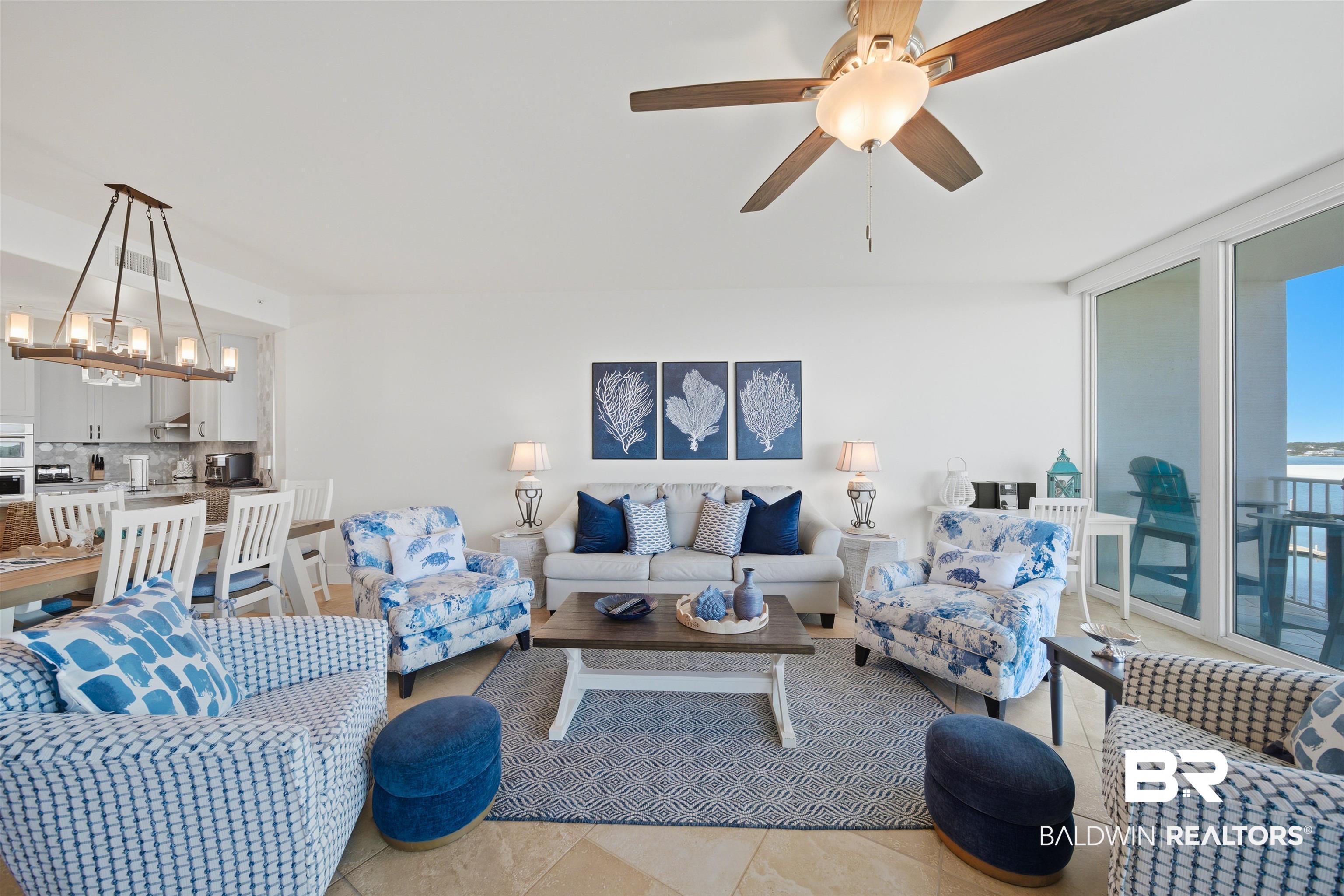 Image 3: Living room featuring a ceiling fan, a chandelier, and expansive windows