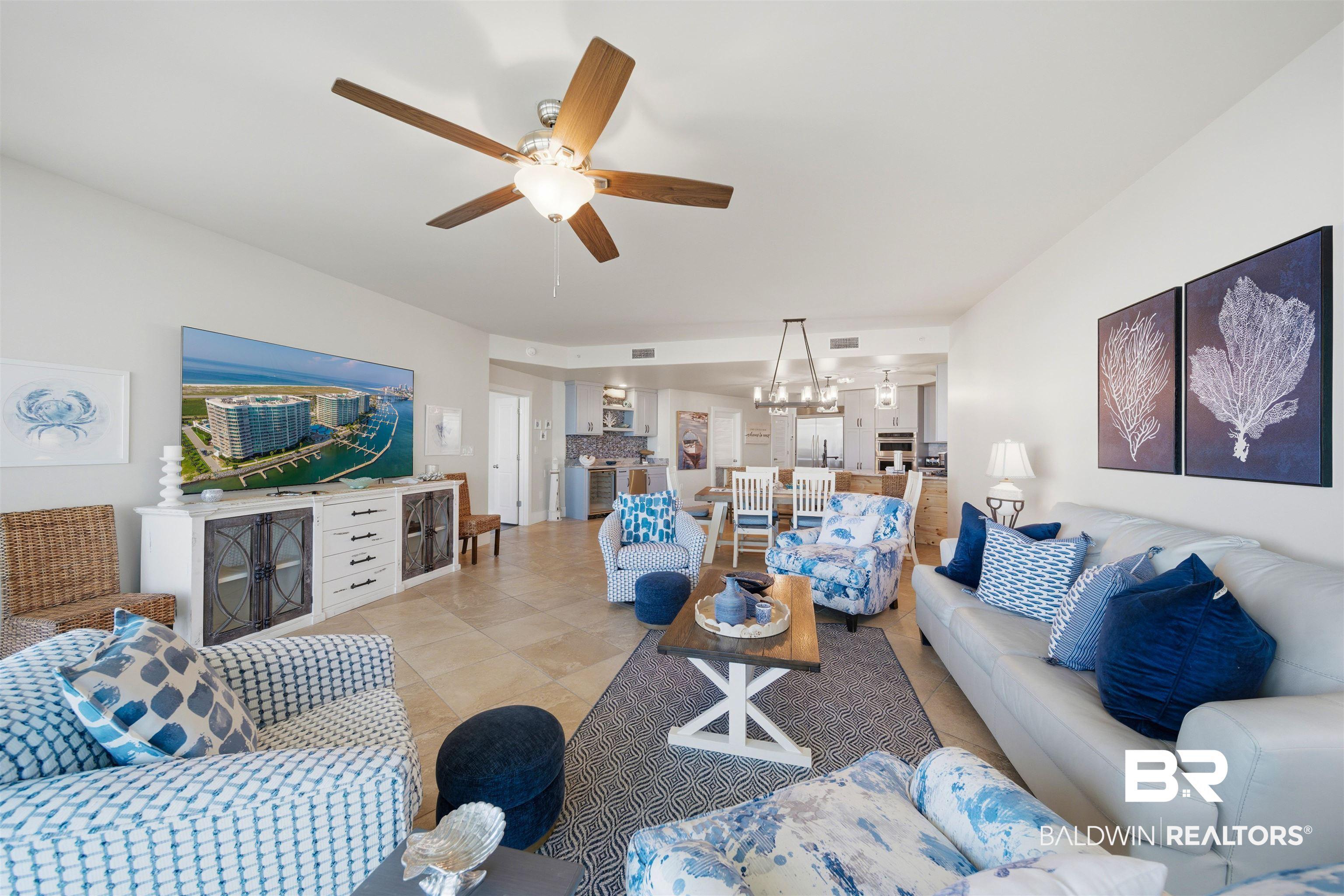 Image 4: Living room with a ceiling fan, hanging lights, and tile patterned floors