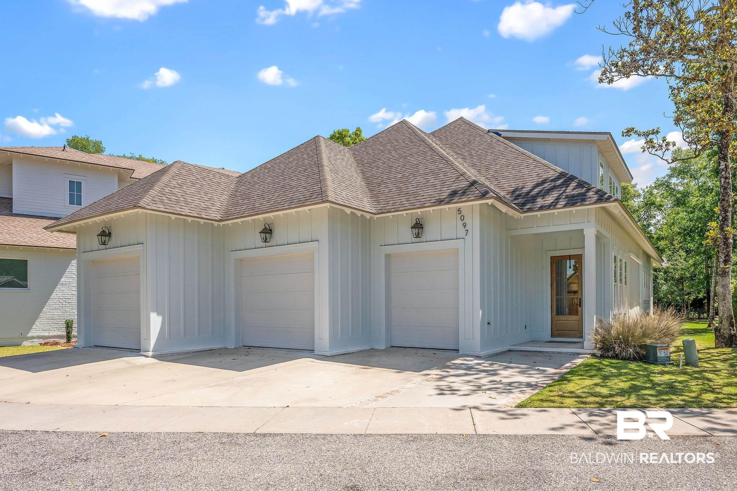 Image 4: Exterior featuring vertical board and batten siding, a prominent multi-car garage with individual doors, a covered front entry with a wood-finish door, and a shingle roof