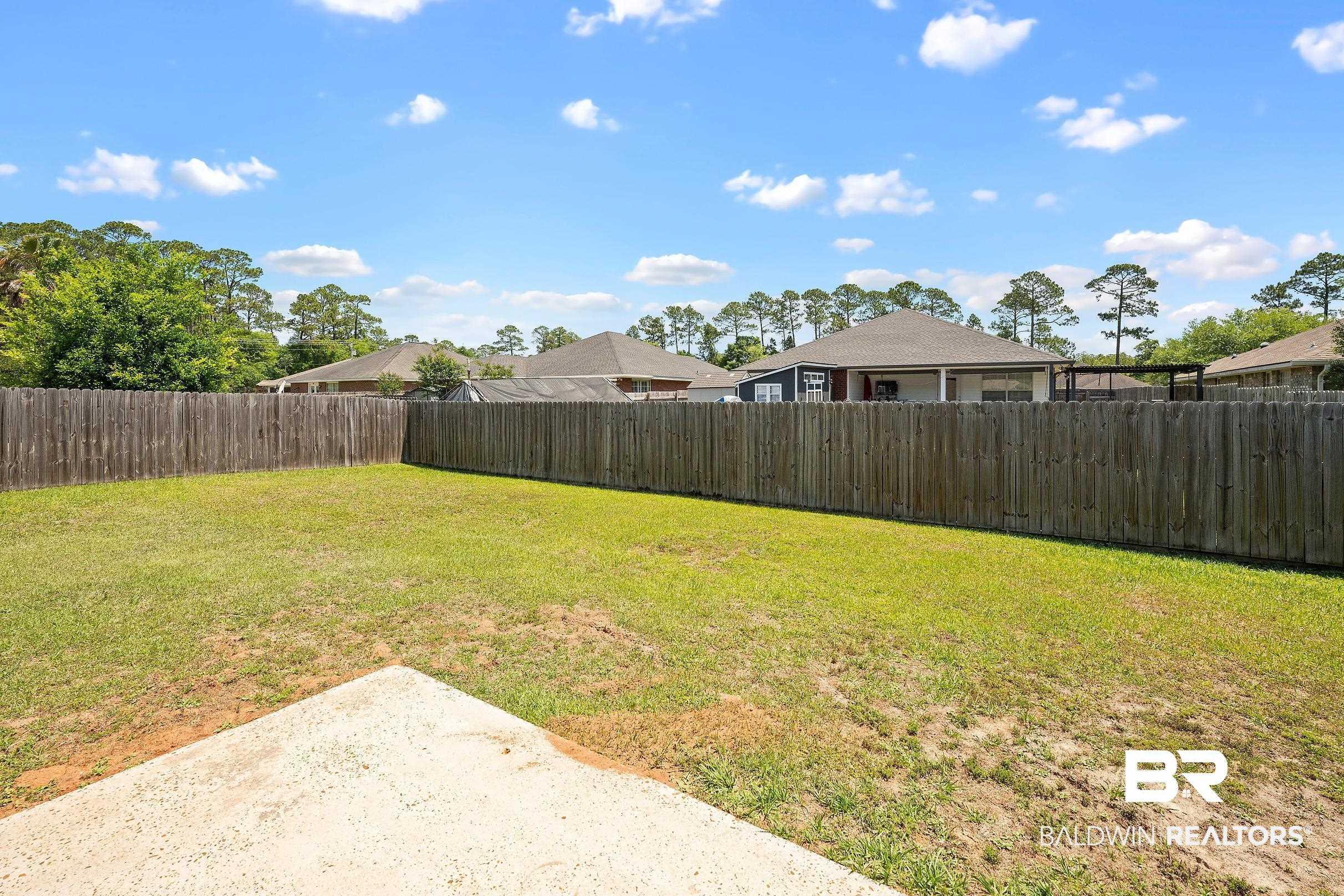 Image 4: Expansive backyard featuring a wood fence perimeter and a concrete patio section