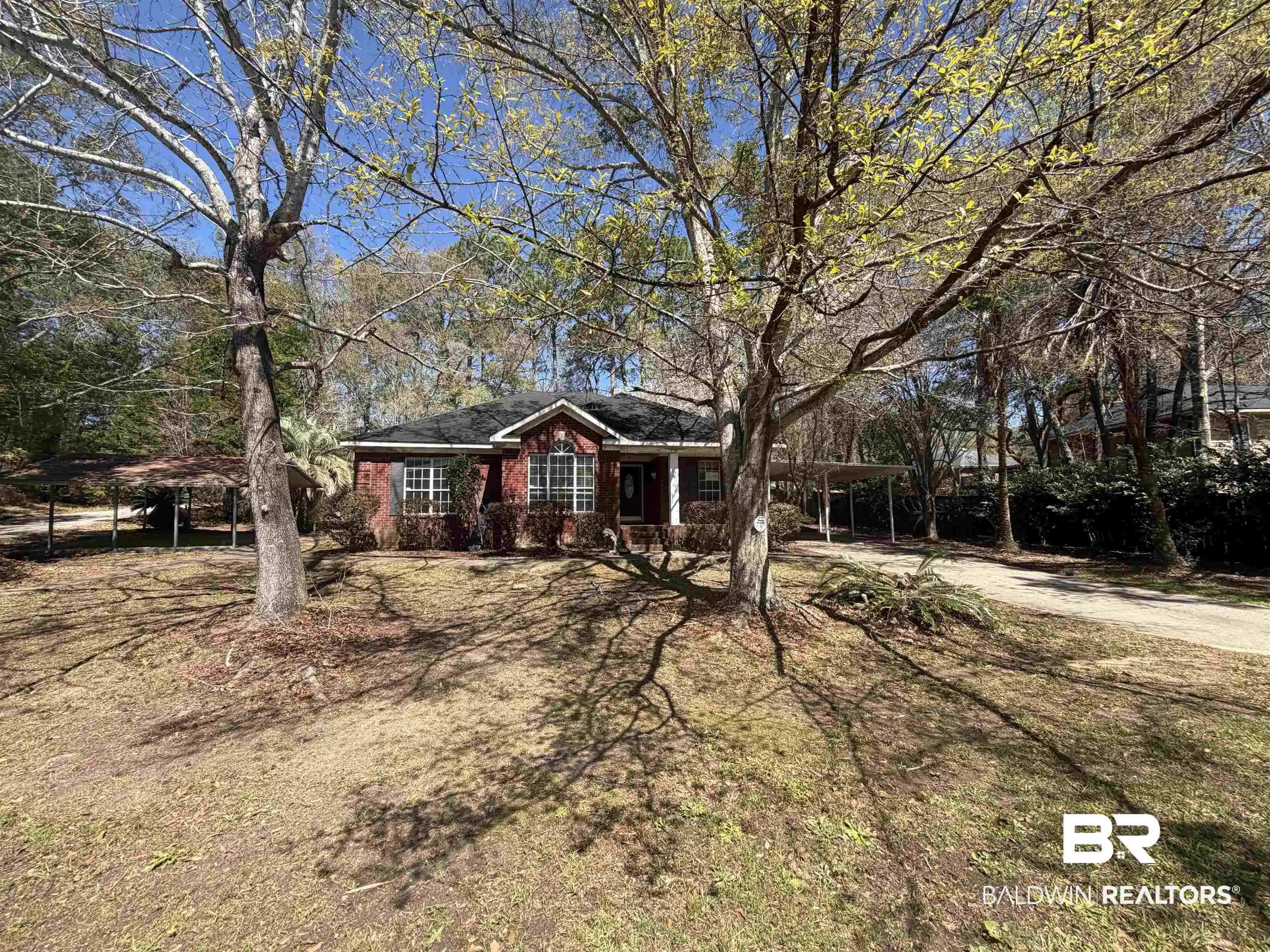 Image 1: Ranch-style house featuring an attached carport, brick siding, covered porch, driveway, and a front yard