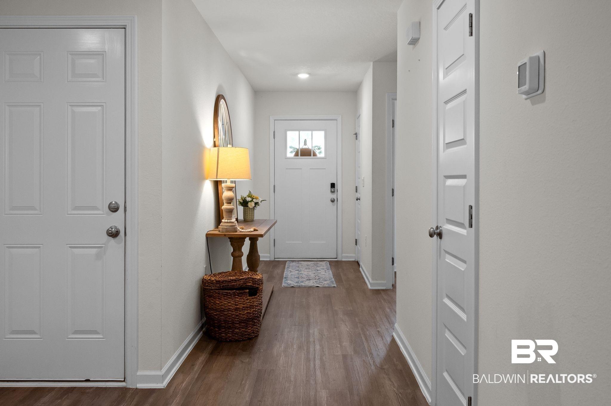 Image 3: Inviting entryway with wood-finish flooring, white walls, and bright overhead lighting