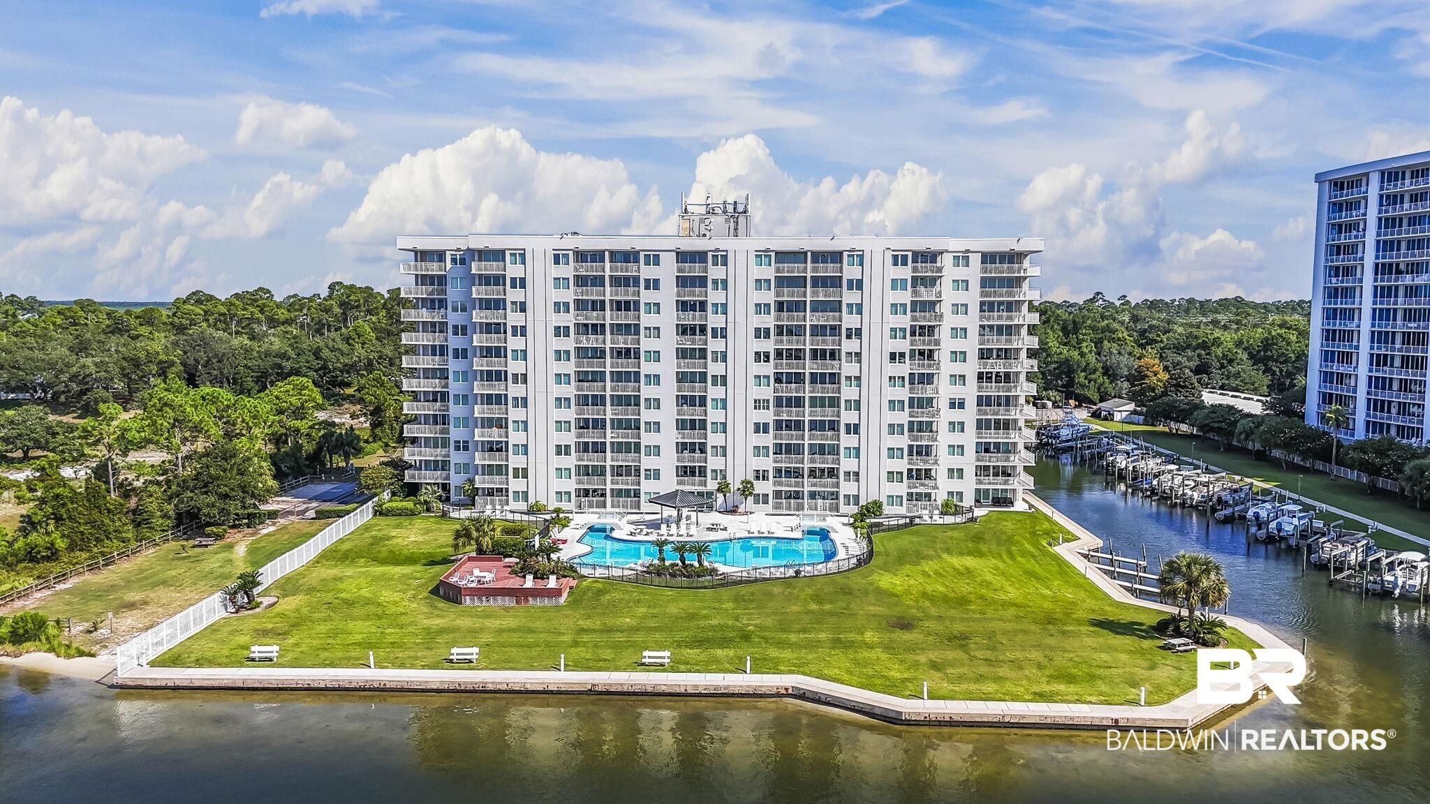 Image 2: High-rise building with multiple balconies, a large outdoor pool, and a manicured green lawn