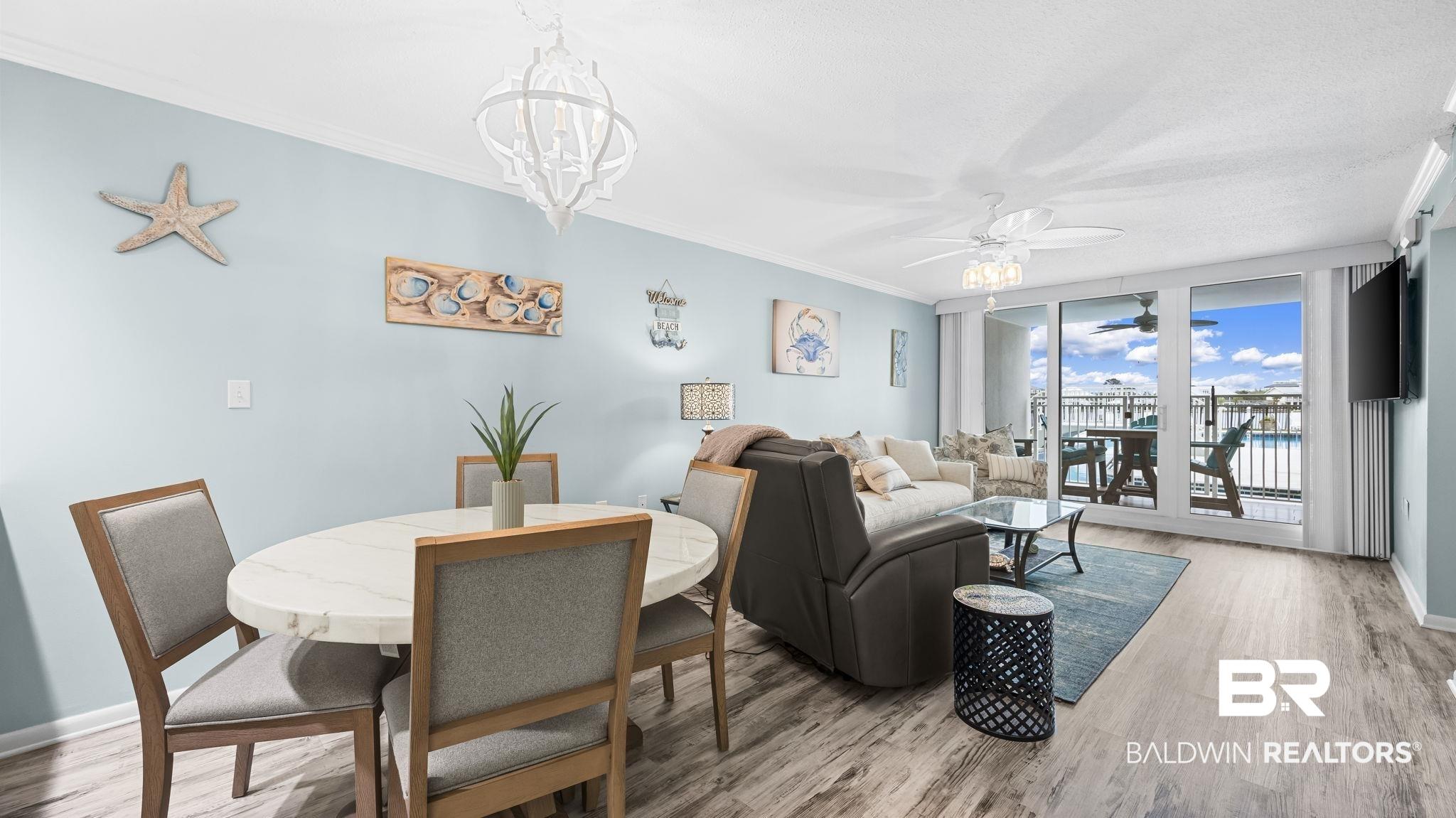 Image 4: Open-concept living area with wood-finish flooring, a white marble-top dining table, and direct access to an outdoor balcony