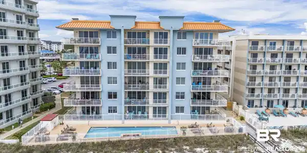 Image 2: Multi-story condominium building featuring a light blue exterior and orange-hued roof