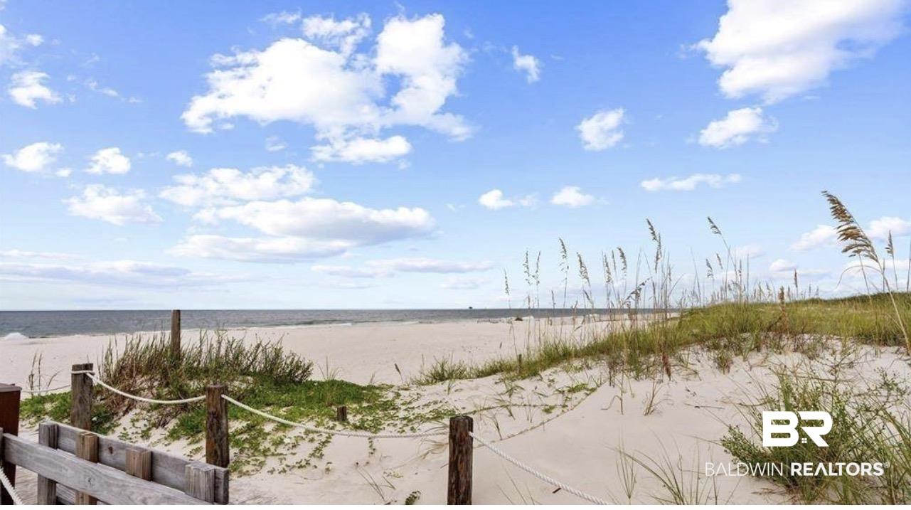 Image 2: Expansive sandy beach with ocean waters and a clear sky with scattered clouds