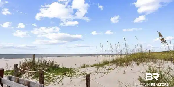 Image 2: Expansive sandy beach with ocean waters and a clear sky with scattered clouds