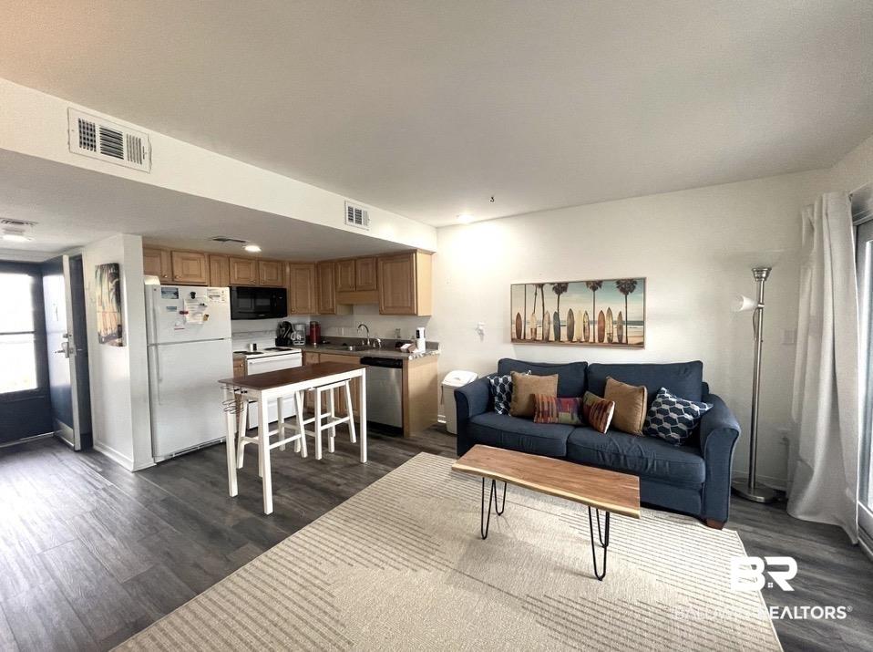 Image 4: Open-concept living area featuring wood-finish flooring, a kitchen with light wood cabinetry, white appliances, and recessed lighting