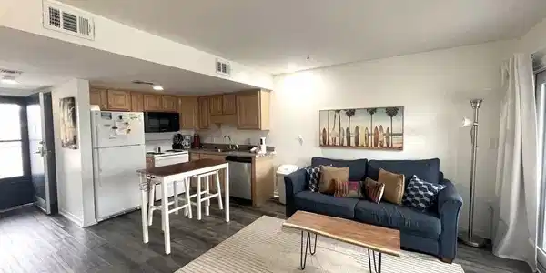 Image 4: Open-concept living area featuring wood-finish flooring, a kitchen with light wood cabinetry, white appliances, and recessed lighting