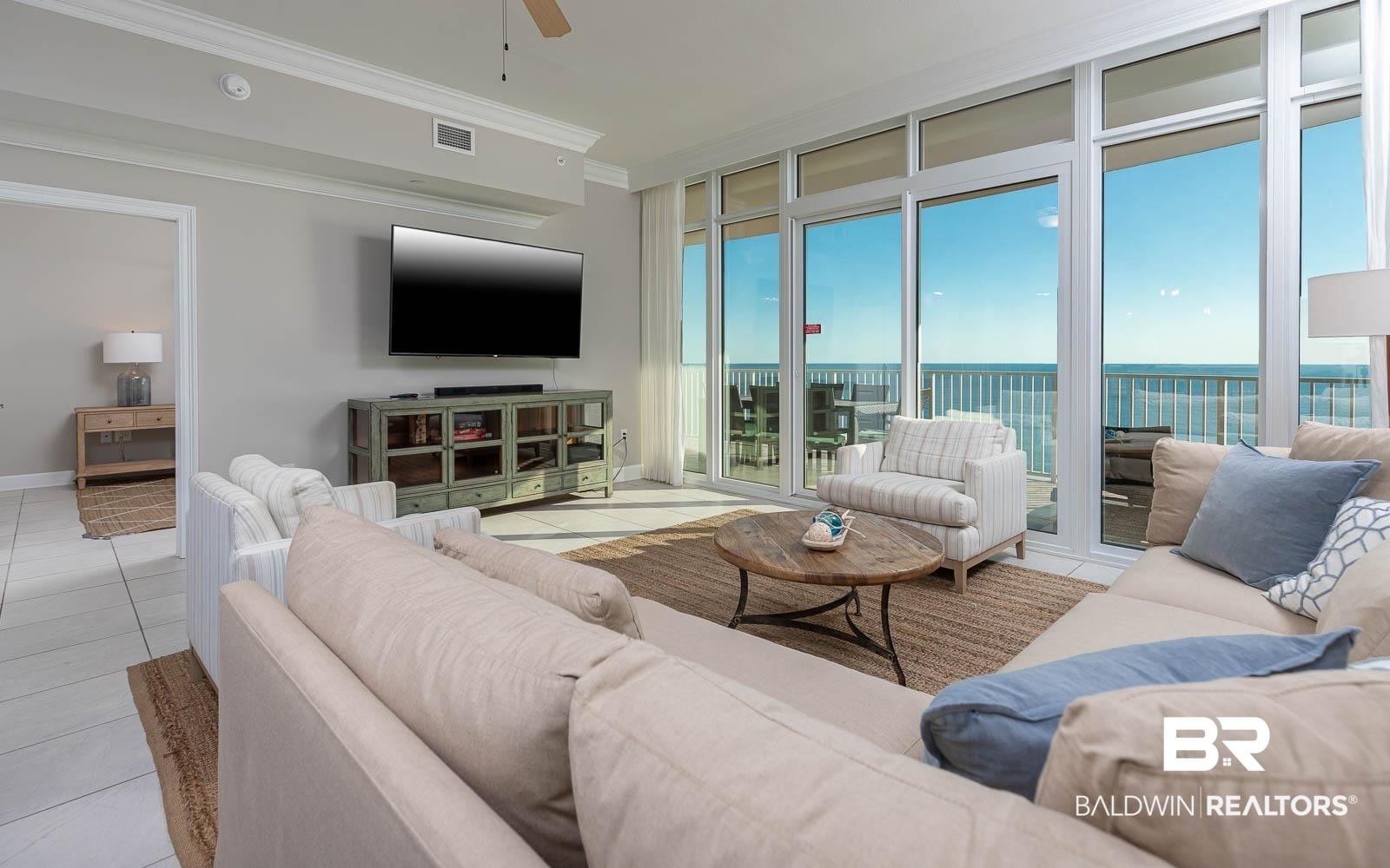 Image 3: Living area with floor to ceiling windows, crown molding, light tile patterned floors, and ceiling fan