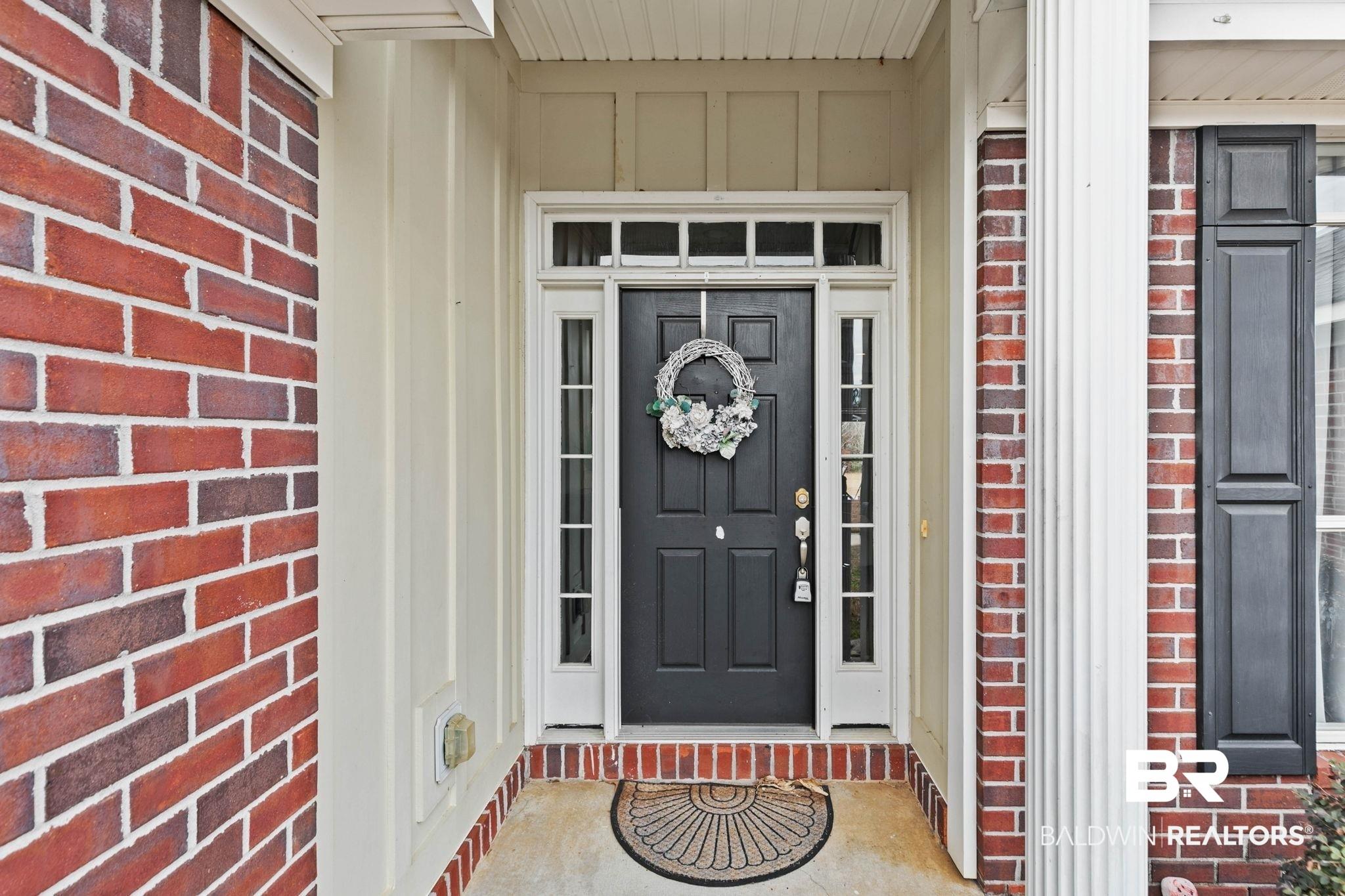 Image 2: View of exterior entry featuring board and batten siding and brick siding