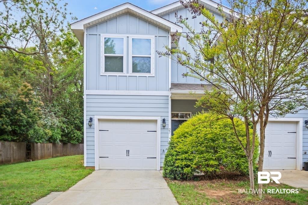 Image 3: View of front of house featuring board and batten siding, an attached garage, and driveway