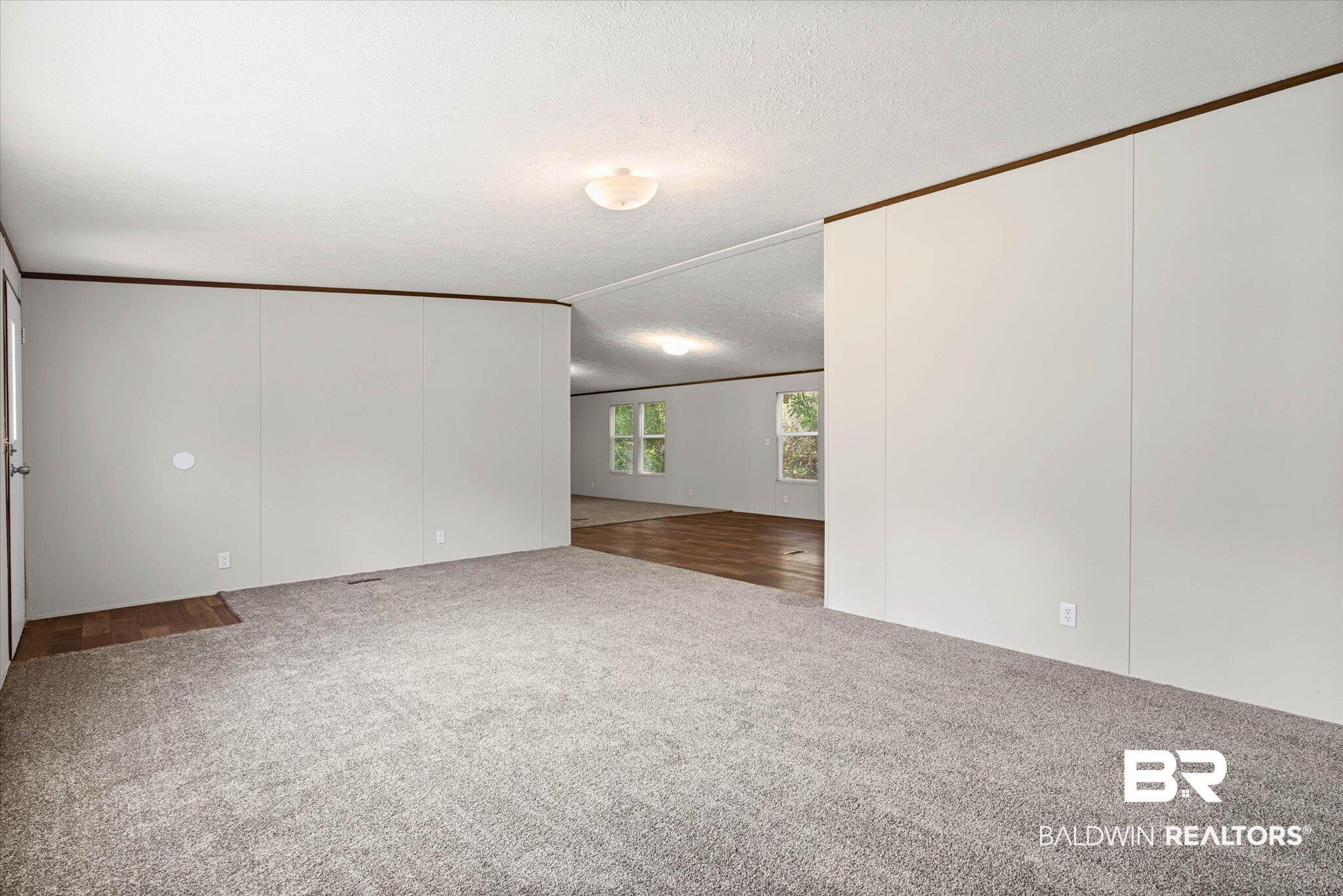 Image 3: Spacious interior featuring neutral carpeting and light-toned walls