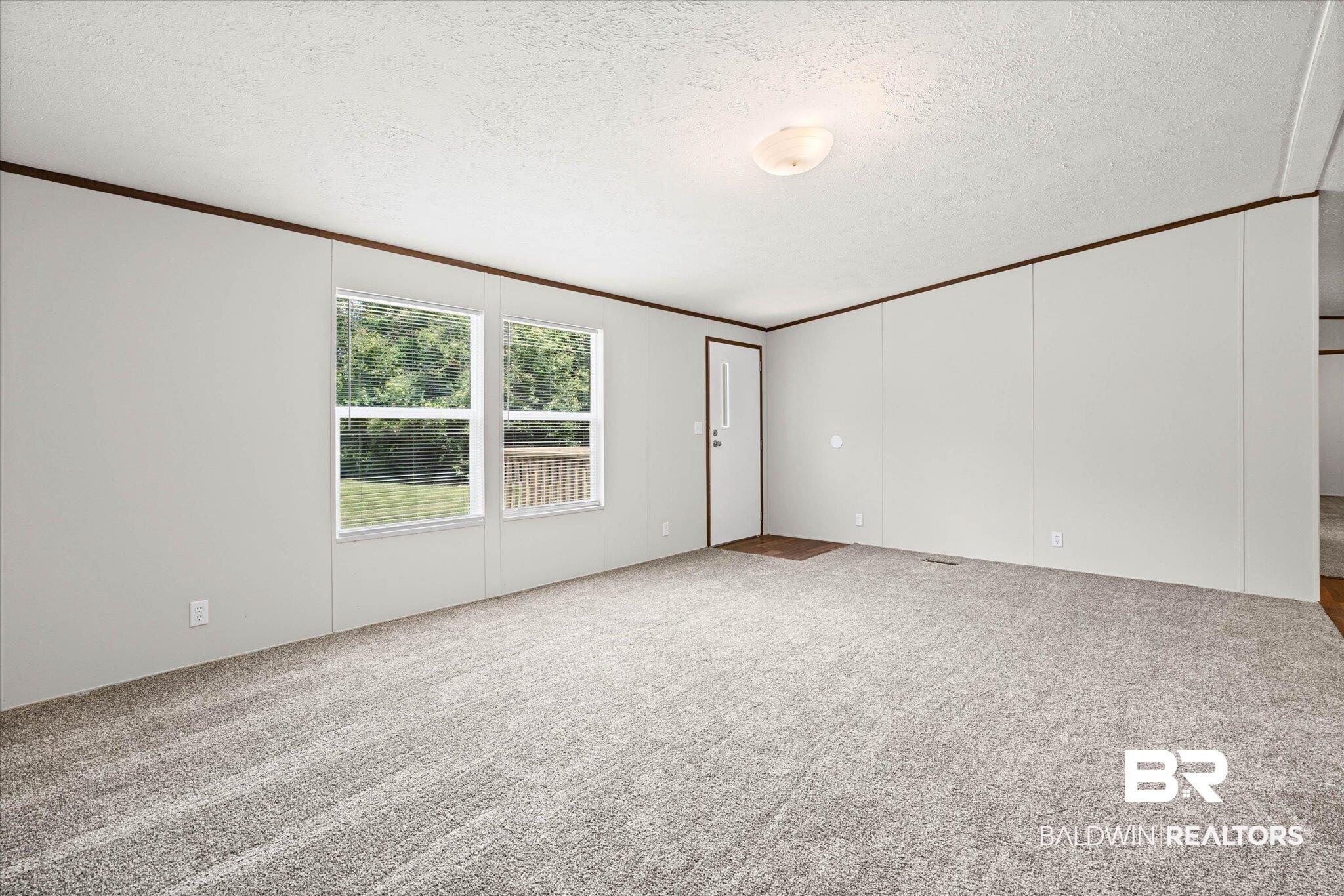 Image 4: Spacious interior room with light gray wall panels and contrasting dark wood trim