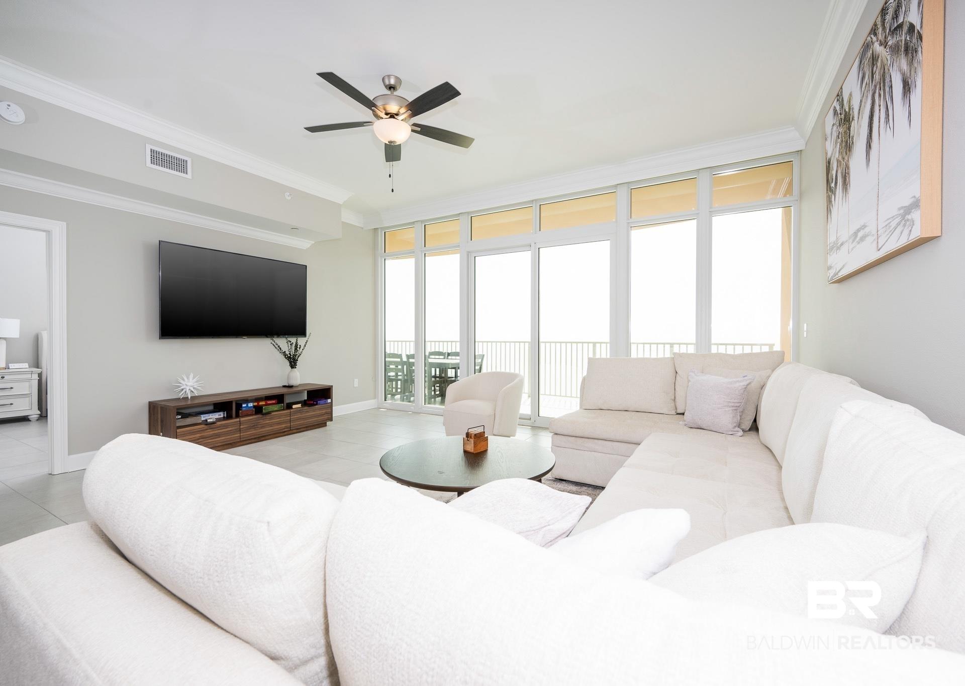 Image 2: Living room with crown molding, floor to ceiling windows, light tile patterned flooring, and a ceiling fan