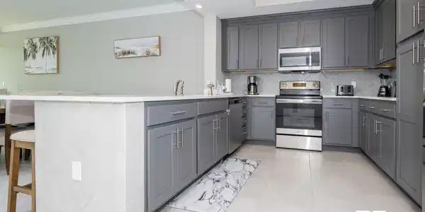 Image 4: Kitchen featuring ornamental molding, appliances with stainless steel finishes, tasteful backsplash, gray cabinets, and a peninsula