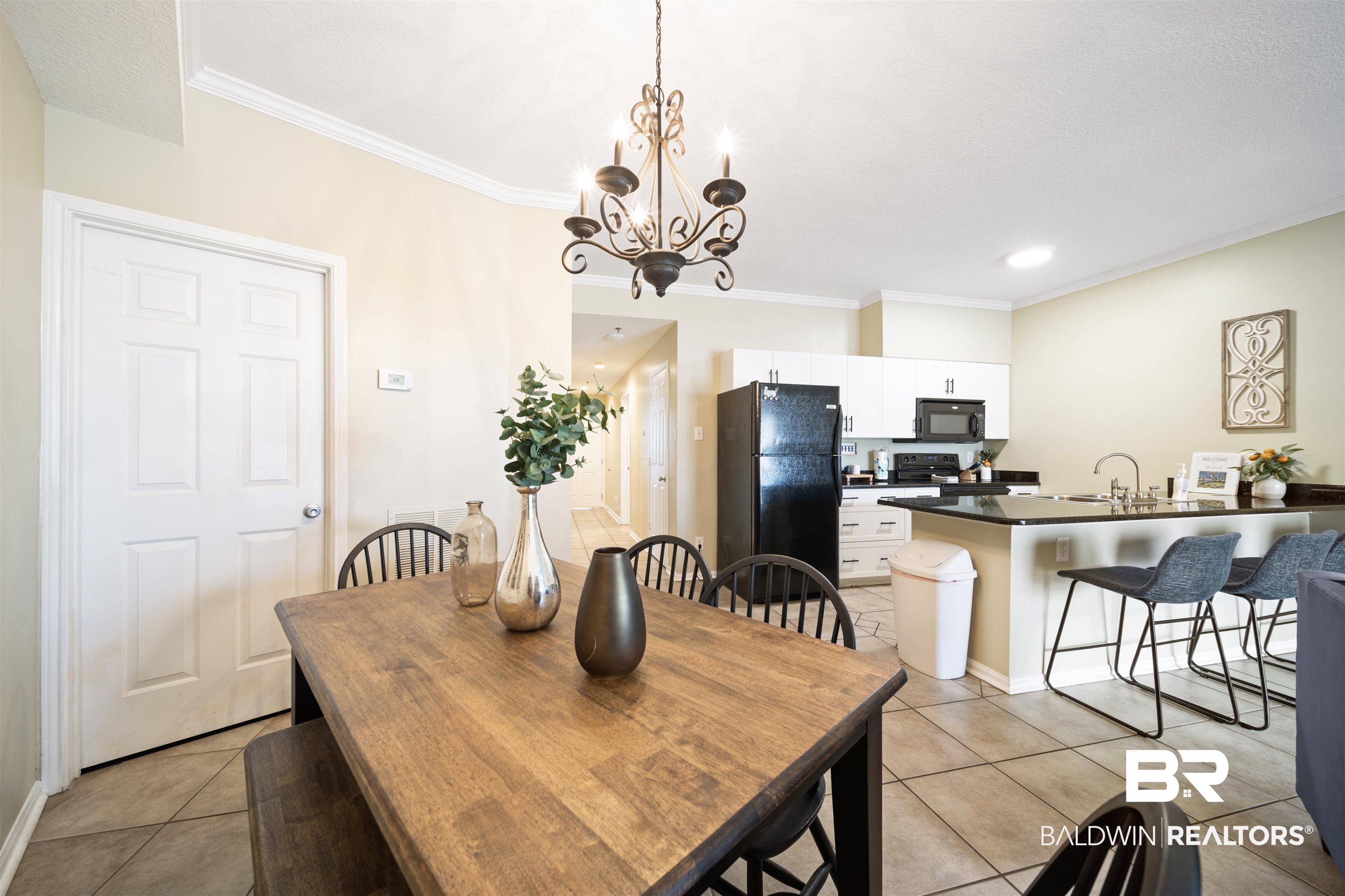 Image 4: Dining space with ornamental molding, light tile patterned floors, and a chandelier