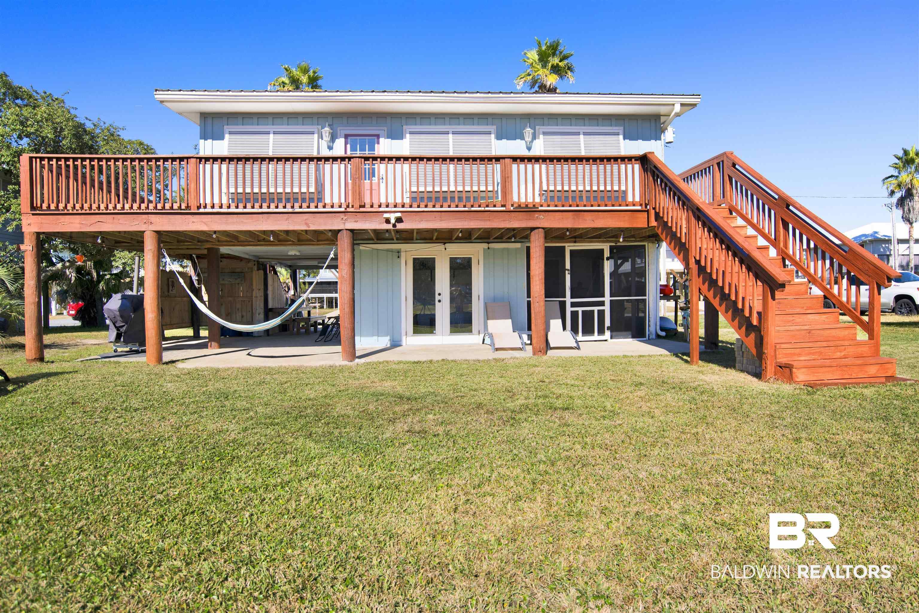 Image 1: Back of property with stairs, a yard, a wooden deck, a patio area, and board and batten siding