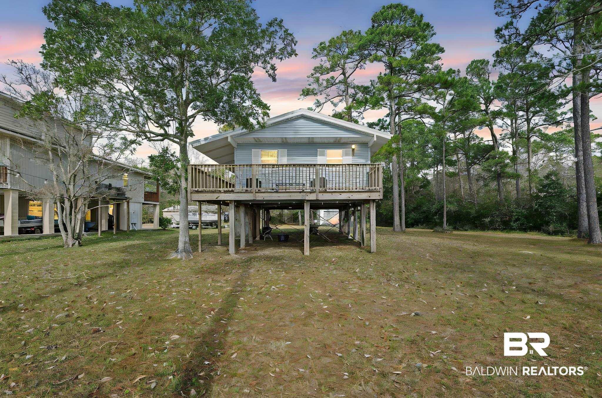 Image 2: Back of house at dusk with a yard, a wooden deck, and a carport