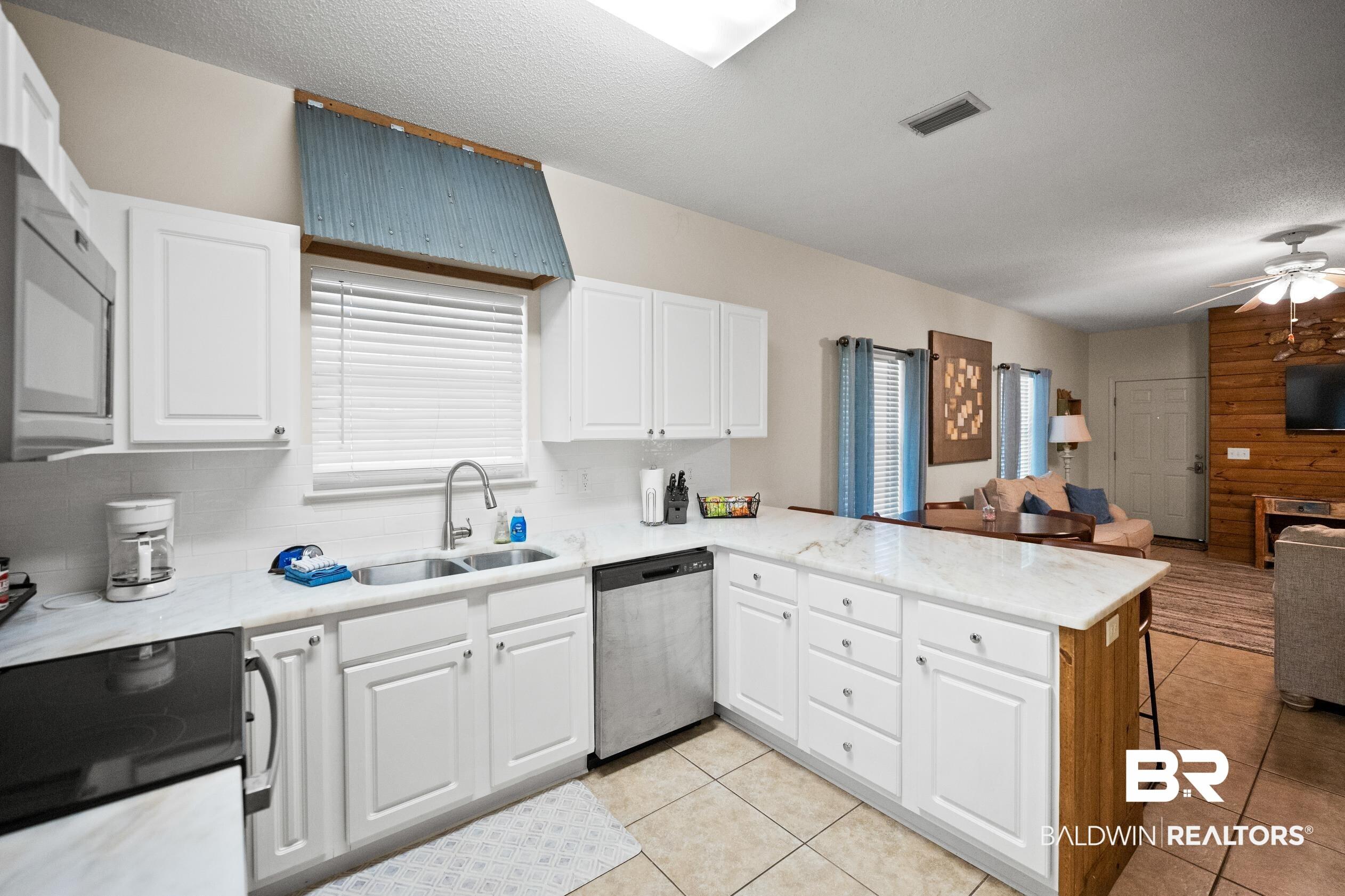 Image 4: Kitchen featuring a peninsula, stainless steel dishwasher, electric stove, healthy amount of natural light, and a textured ceiling