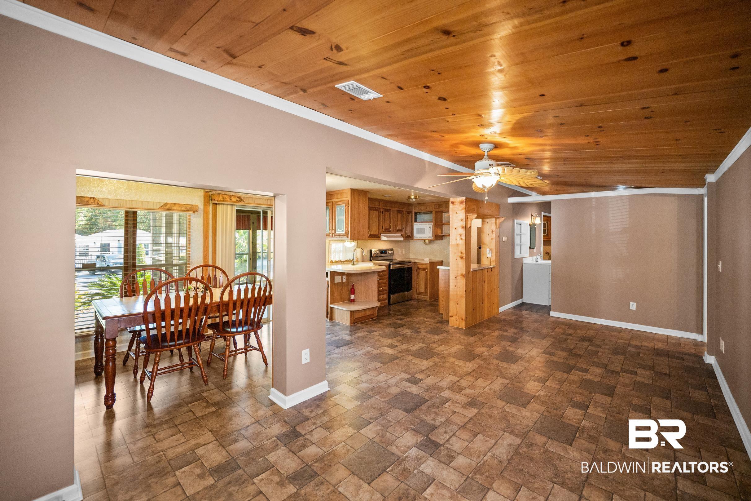 Image 3: Open concept living, kitchen, and dining with wood ceiling, wood plank flooring, and ceiling fan