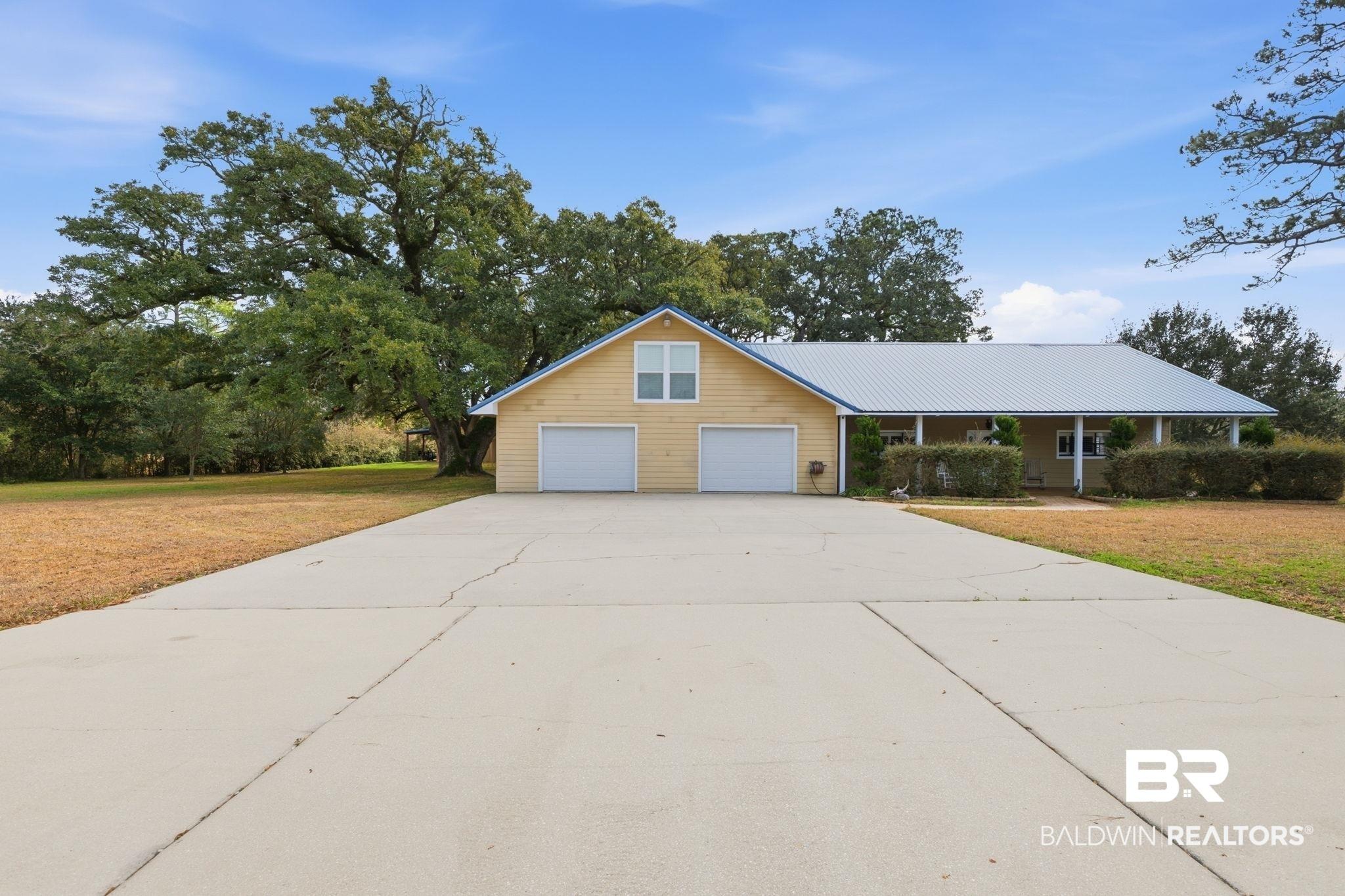 Image 2: View of front of house with a front yard, concrete driveway, and a metal roof