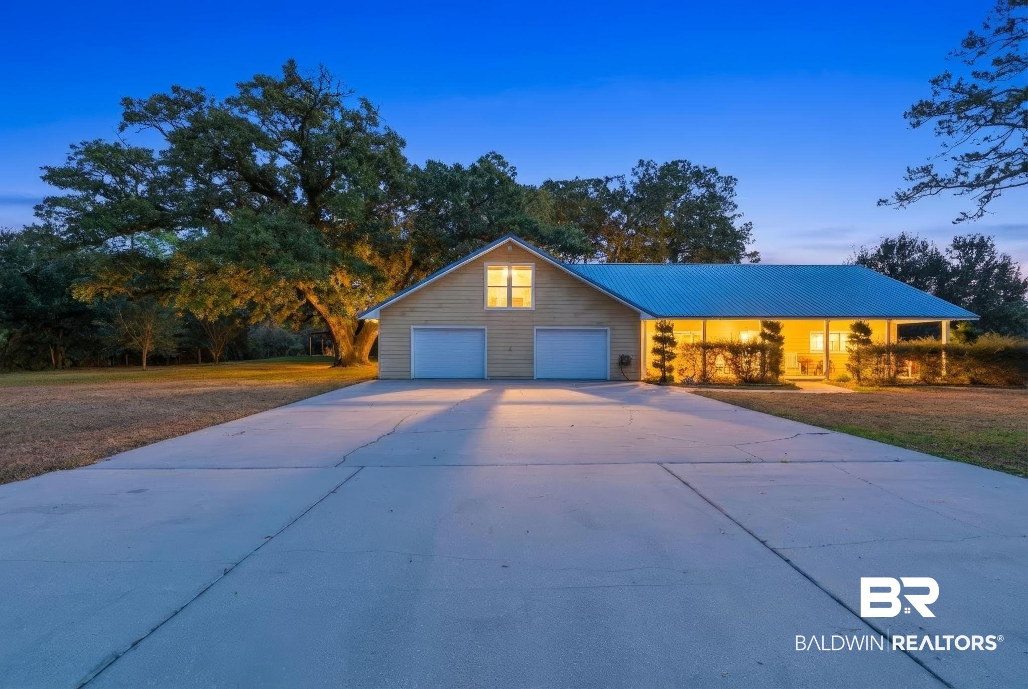 Image 3: View of front of home featuring concrete driveway, a metal roof, and an attached garage