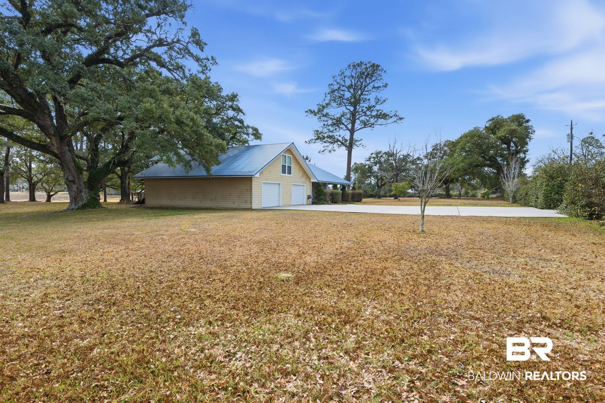 Image 4: View of grassy yard with a garage and concrete driveway