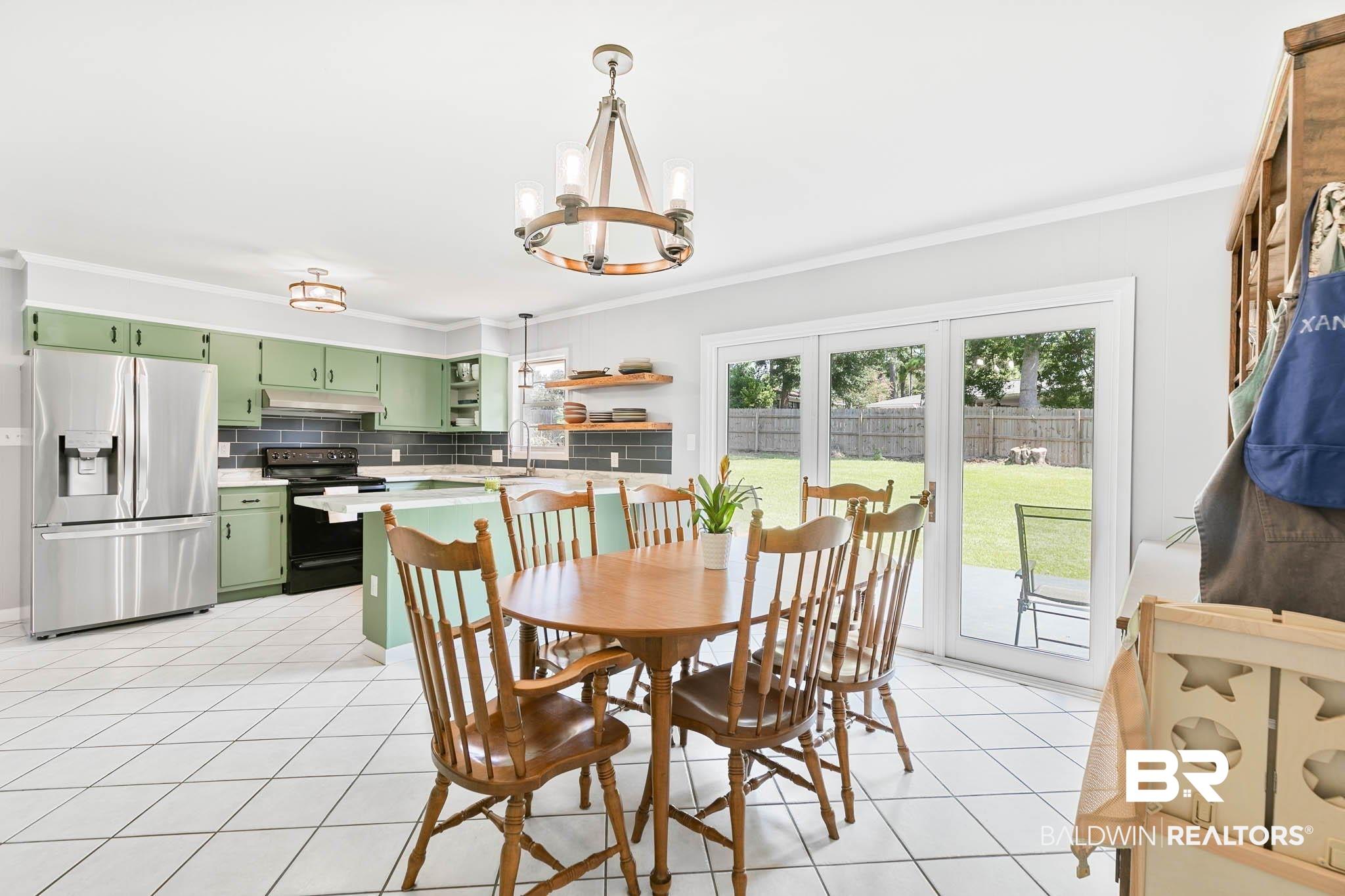 Image 4: Dining area with a chandelier, light tile patterned floors, and ornamental molding