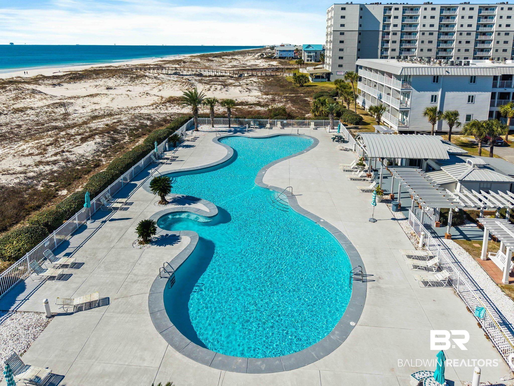 Image 3: Expansive serpentine swimming pool with integrated spa, surrounded by a paved deck
