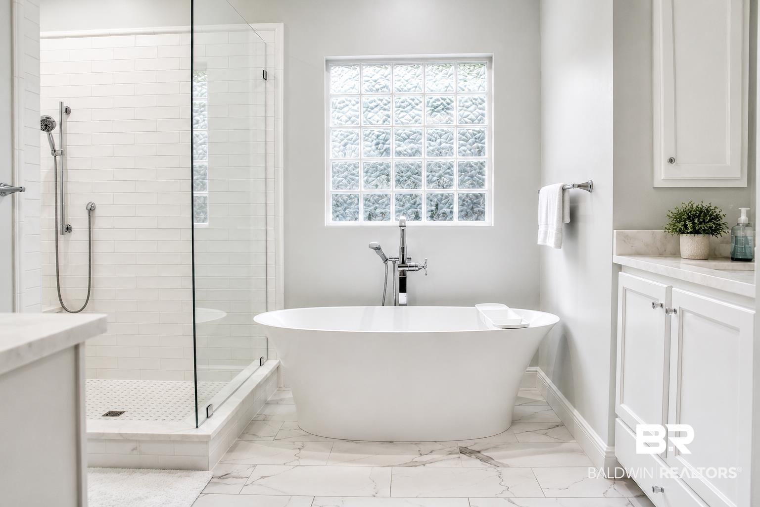 Image 3: Freestanding soaking tub with chrome fixtures, accompanied by a glass-enclosed shower featuring white subway tile surround and a tiled floor