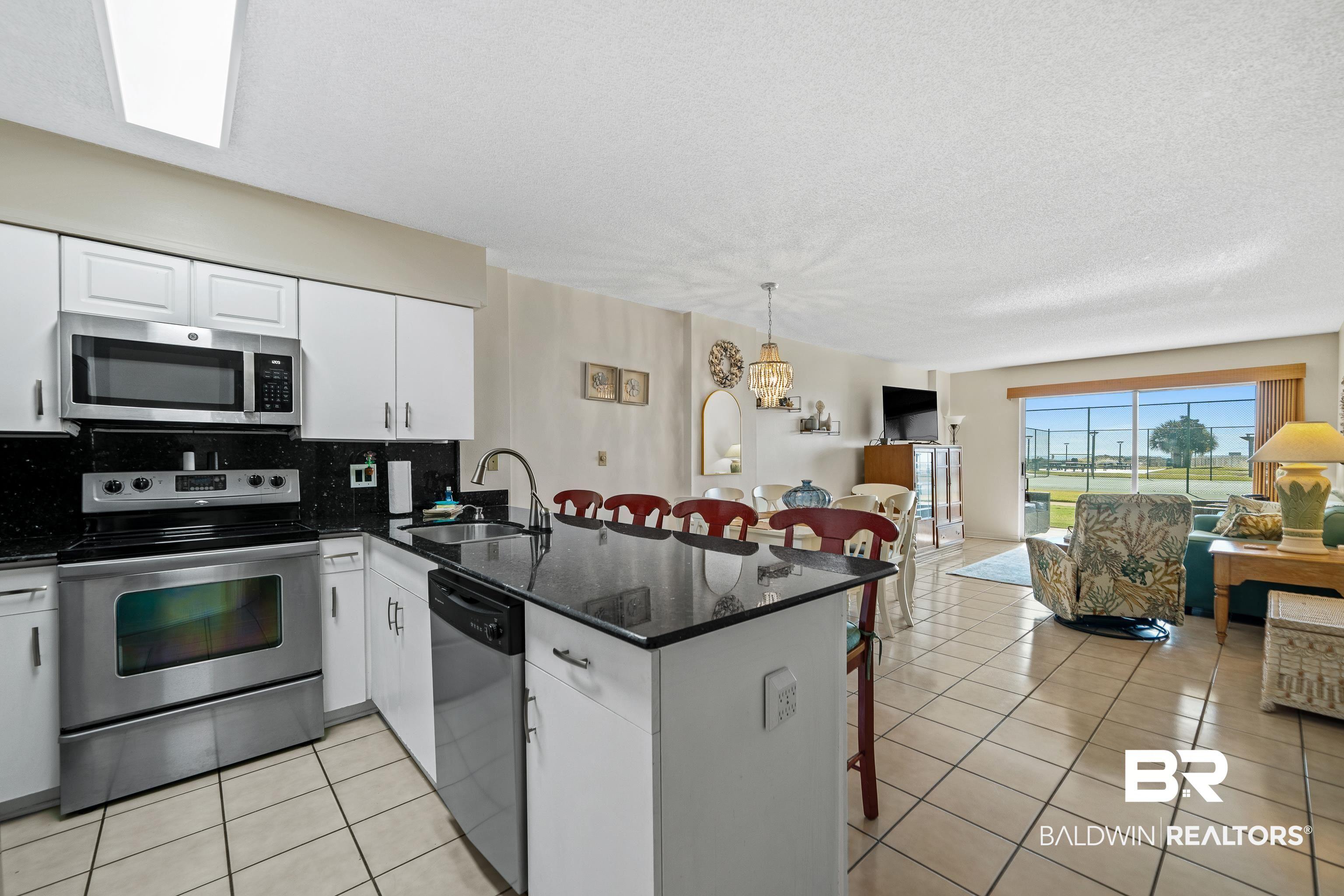 Image 4: Kitchen with a breakfast bar, appliances with stainless steel finishes, dark stone counters, open floor plan, and a peninsula