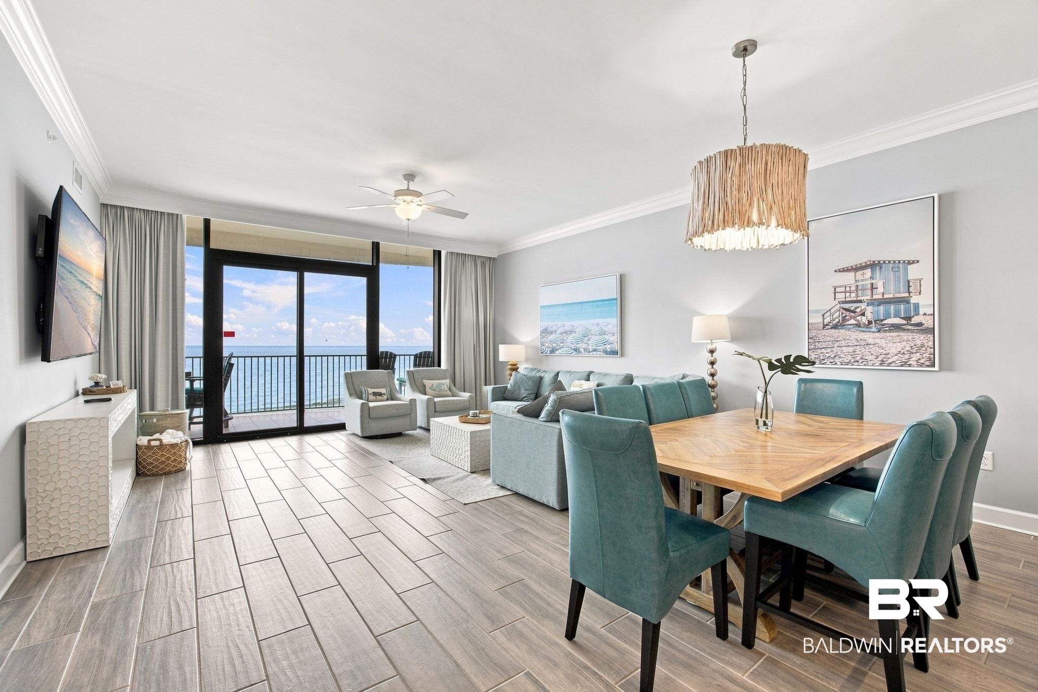 Image 3: Open-concept living and dining area featuring wood-finish tile flooring, crown molding, and a ceiling fan