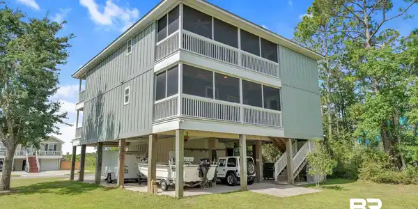 Image 4: Rear view of property with a sunroom, a carport, stairway, and a lawn