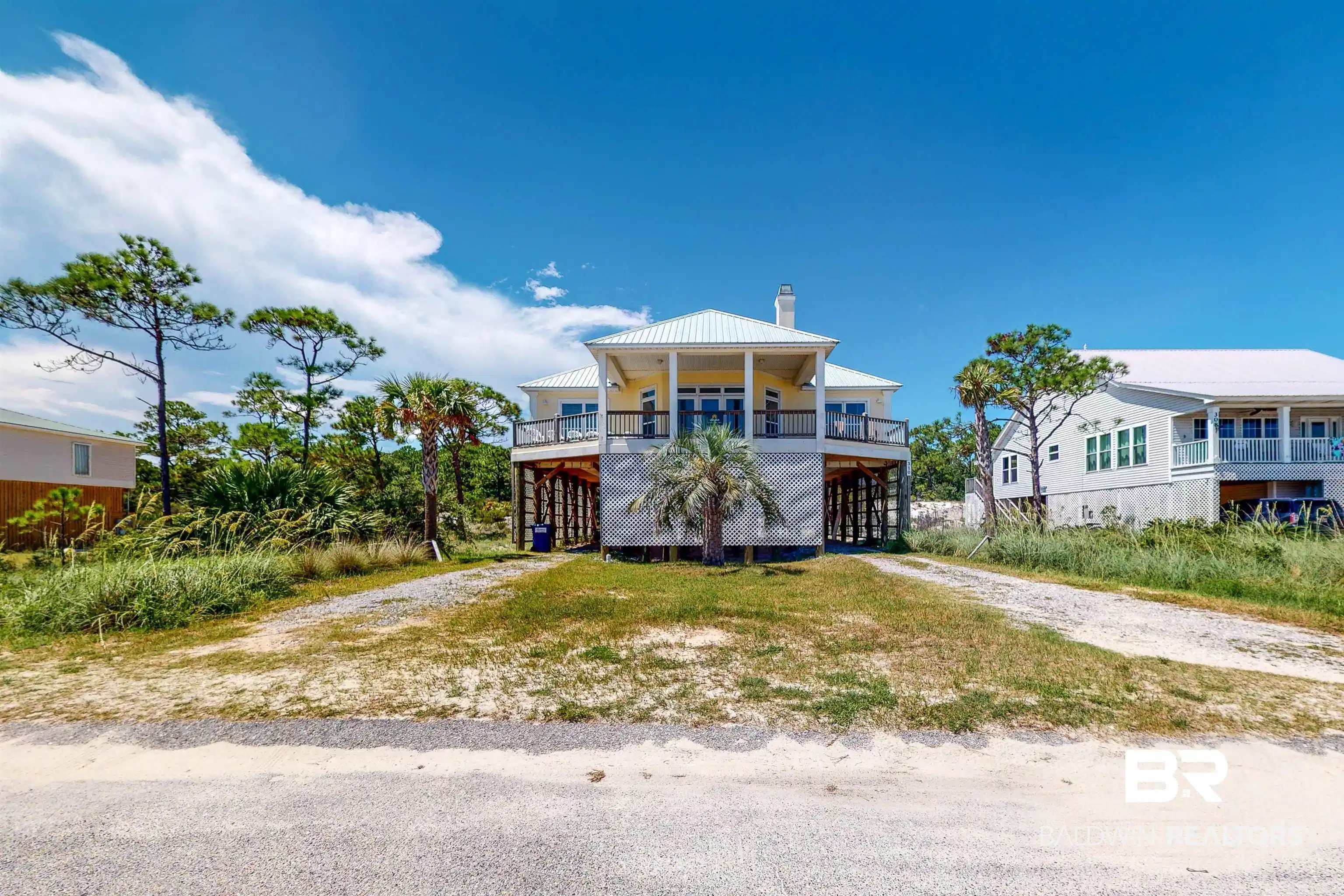 Image 1: Coastal home featuring a carport, dirt driveway, a chimney, and a metal roof