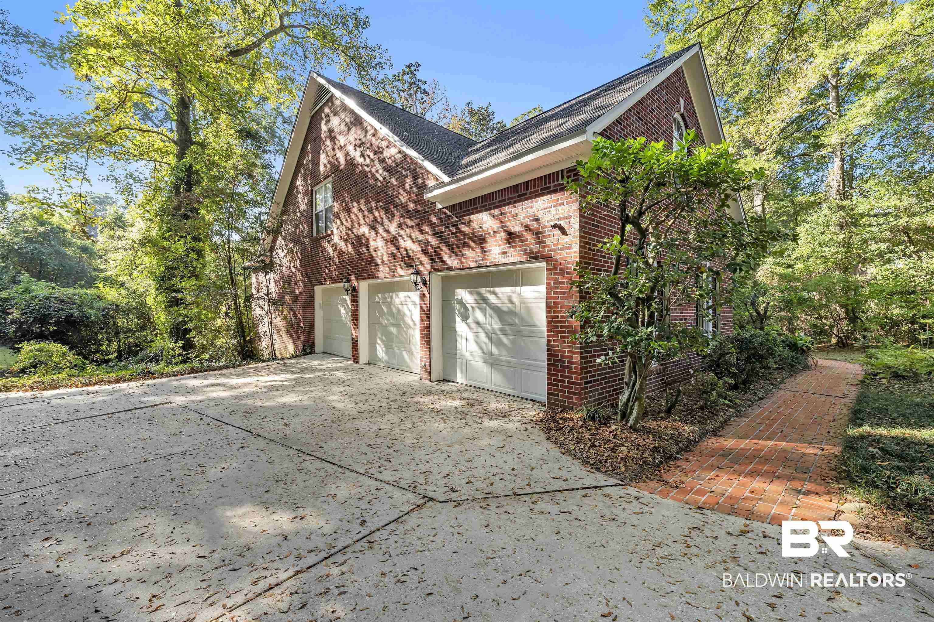 Image 3: View of side of home with concrete driveway and brick siding